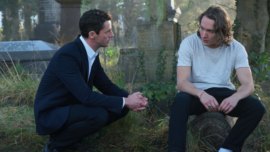 Matthew (Matthew Goode), accroupi,  discute avec Jack (Toby Regbo) alors qu'il est calmé, assis sur une tombe